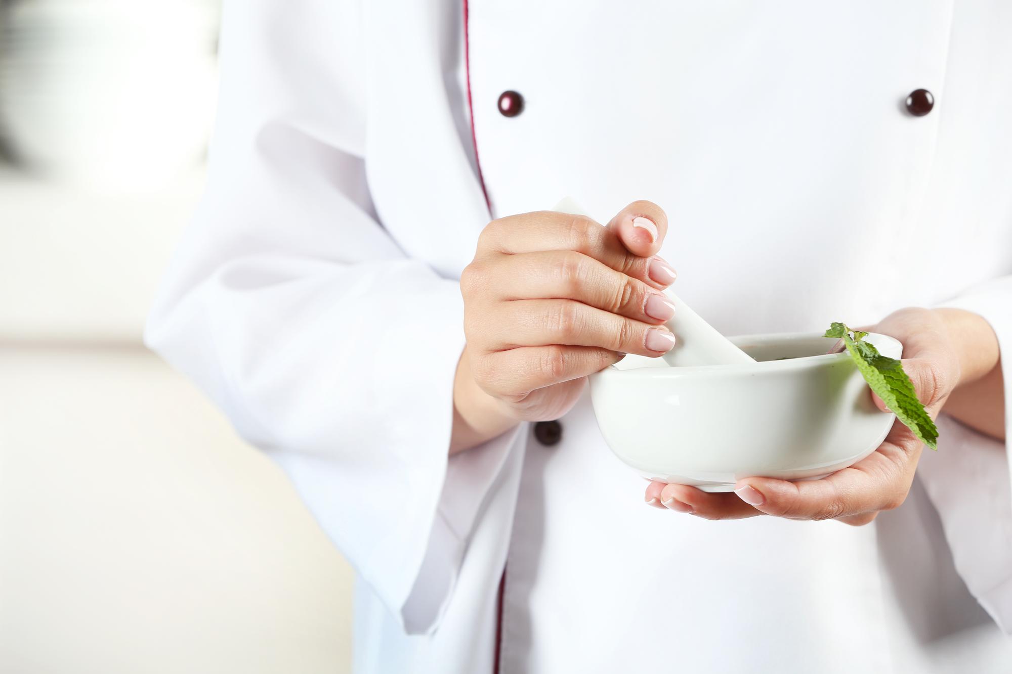 chef holding fresh herbs over a bowl